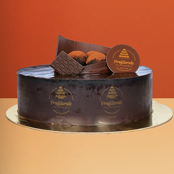 Chocolate Mousse Cake Chocolate mousse cake with glossy dark chocolate ganache wafer rolls and cocoa truffles on top by Profiterole Patisserie