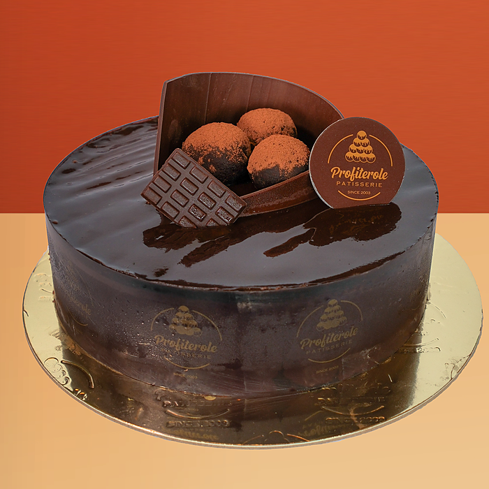 Chocolate mousse cake with glossy dark chocolate ganache wafer rolls and cocoa truffles on top by Profiterole Patisserie