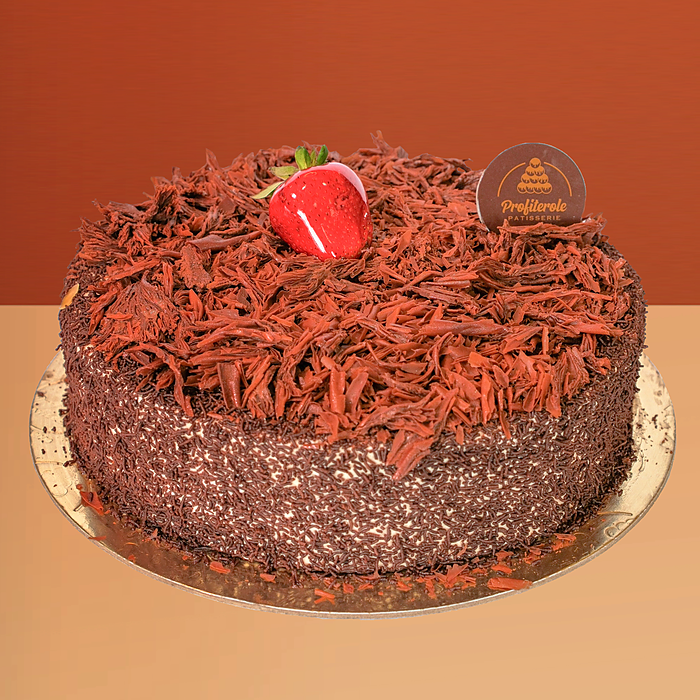 Black forest cake covered in chocolate shavings and flakes with a fresh strawberry on top by Profiterole Patisserie
