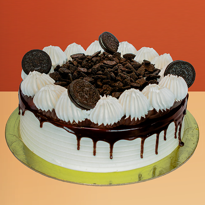Oreo ice cream cake with white cream base chocolate sauce drip Oreo cookies & cream dollops on top by Profiterole Patisserie