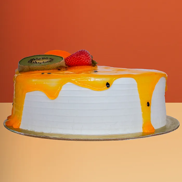 Round ice cream cake with passionfruit sauce drip decorated with a kiwi slice and fresh strawberry by Profiterole Patisserie