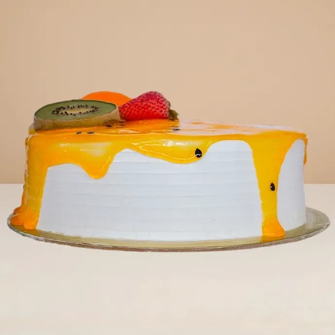 side view of the round ice cream cake showing the base vanilla sponge and some passionfruit sauce dripping