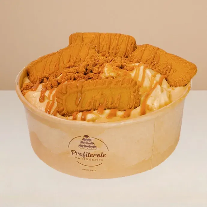 lotus biscoff ice cream in a bowl drizzled with sweet syrup and topped with whole and crumbled lotus biscuits