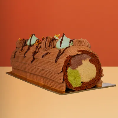 Chocolate Swiss roll ice cream cake with chocolate ganache piping showing hazelnut pistachio and chocolate gelato inside