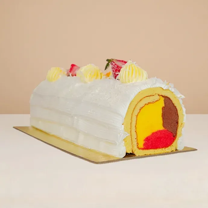 side view of the mango swiss roll ice cream cake, vanilla sponge wrapping the chocolate, strawberry, and mango ice cream