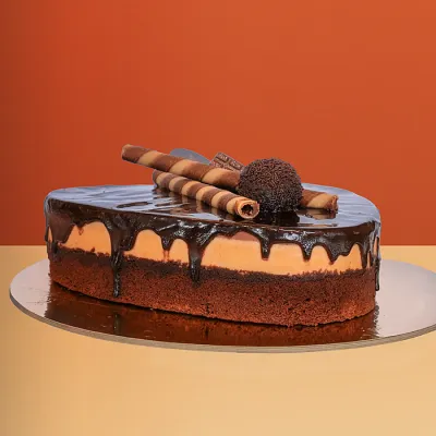 Heart-shaped trio cake with chocolate ganache drip wafer rolls and a chocolate truffle ball on top by Profiterole Patisserie