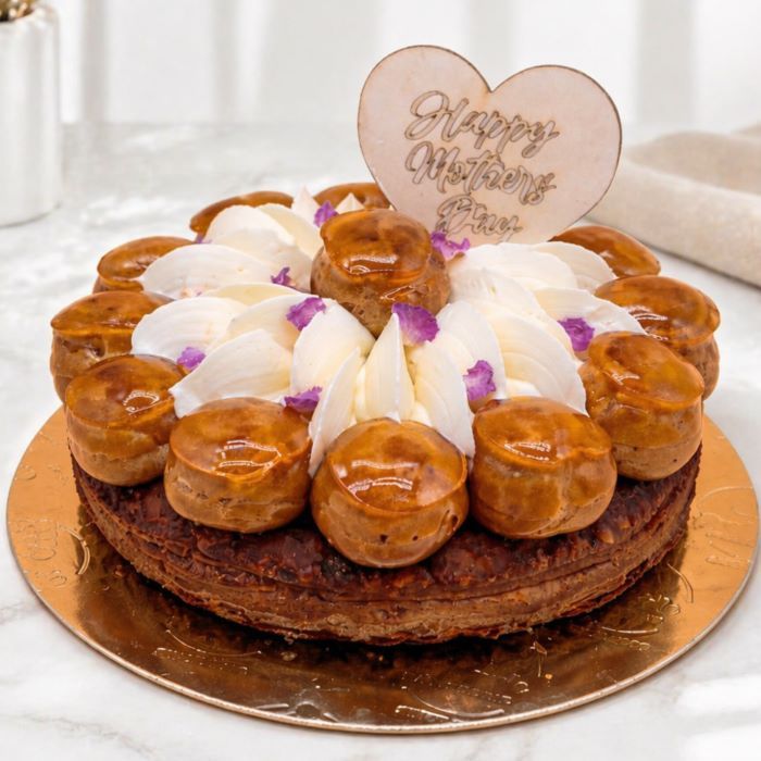 St Honoré cake with a layered mille-feuille base, filled with custard and topped with caramel-glazed profiteroles 