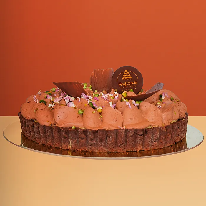 Dubai chocolate tart cake w/ chocolate cream rosettes pistachios & rose petals on a chocolate base by Profiterole Patisserie