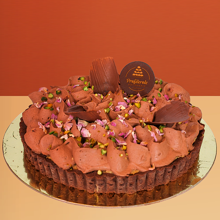 Dubai chocolate tart cake w/ chocolate cream rosettes pistachios & rose petals on a chocolate base by Profiterole Patisserie