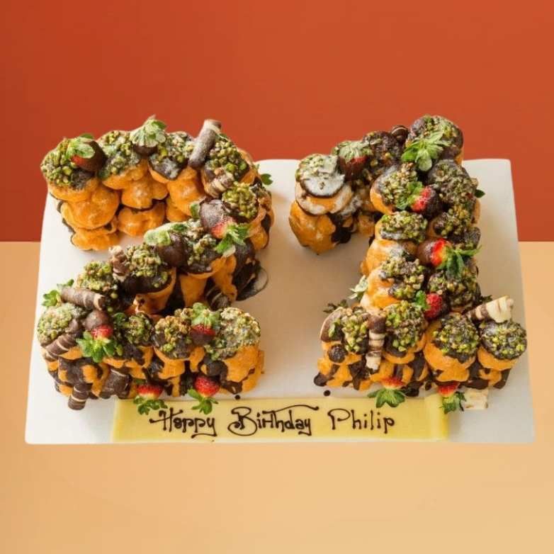 Profiterole number 21 birthday cake with chocolate, pistachios, and strawberries