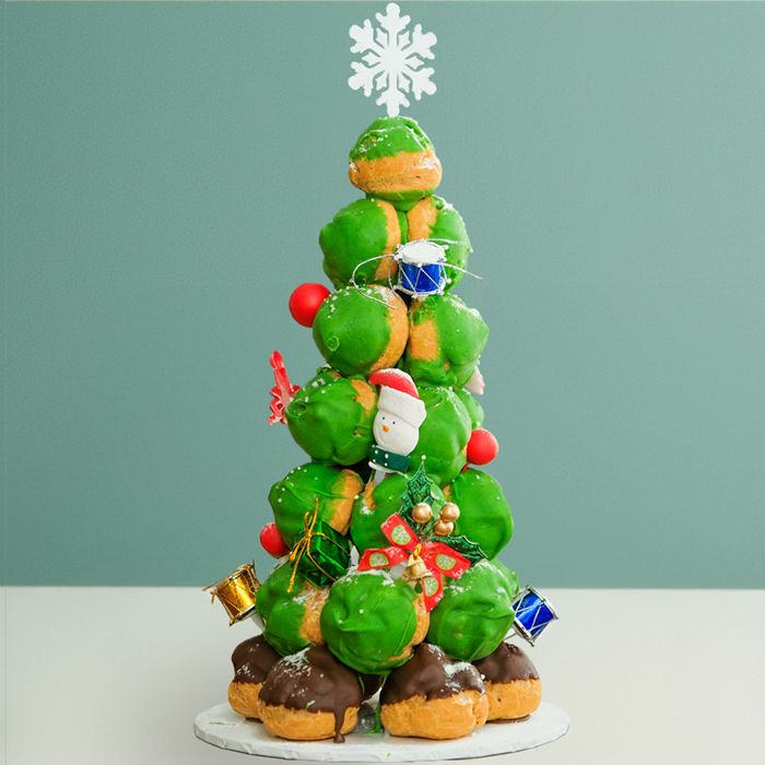 A green Christmas tree cake made from Profiteroles towering with a white snowflake as the star