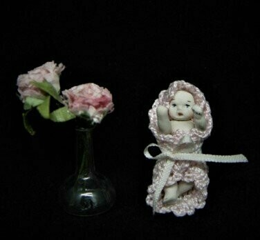 Bebé en miniatura envuelto en toquilla rosa de perlé