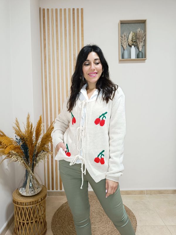 Rebeca beige de punto con dibujo de cerezas, anudada por la parte central con largos cordones.