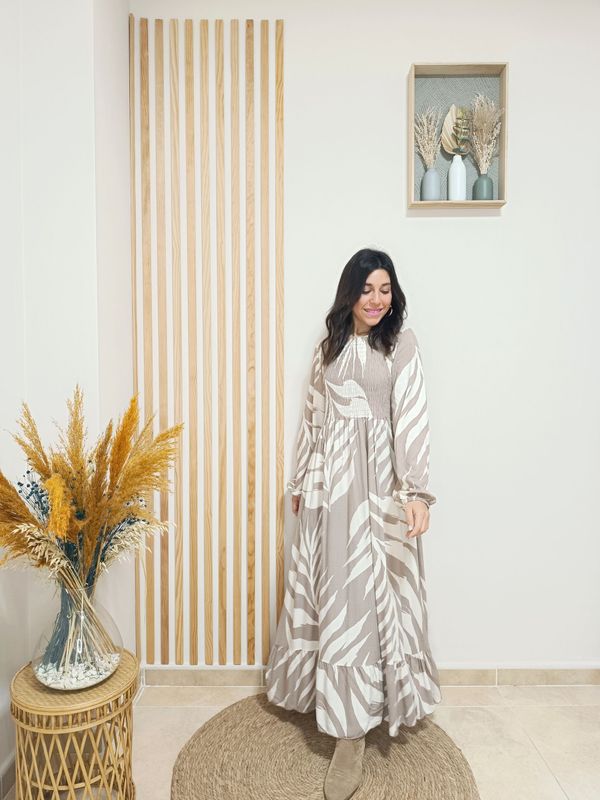 Vestido largo con volante inferior en color marrón y con un estampado de grandes hojas blancas, con nido de abeja por la parte del pecho y espalda, y puños engomados