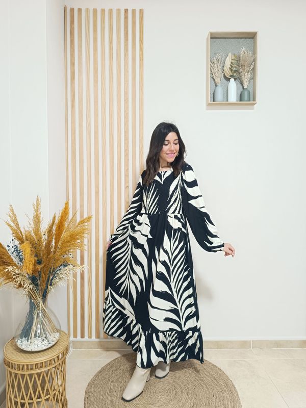 Vestido largo en color negro con estampado de hojas grandes en color blanco, con nido de abeja por la parte del pecho y espalda, puños engomados y volante inferior