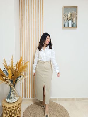 Falda cámel con silueta tubo y cintura alta, adornada con unos botones dorados en el filo de ambos bolsillos y abertura central por la parte delantera