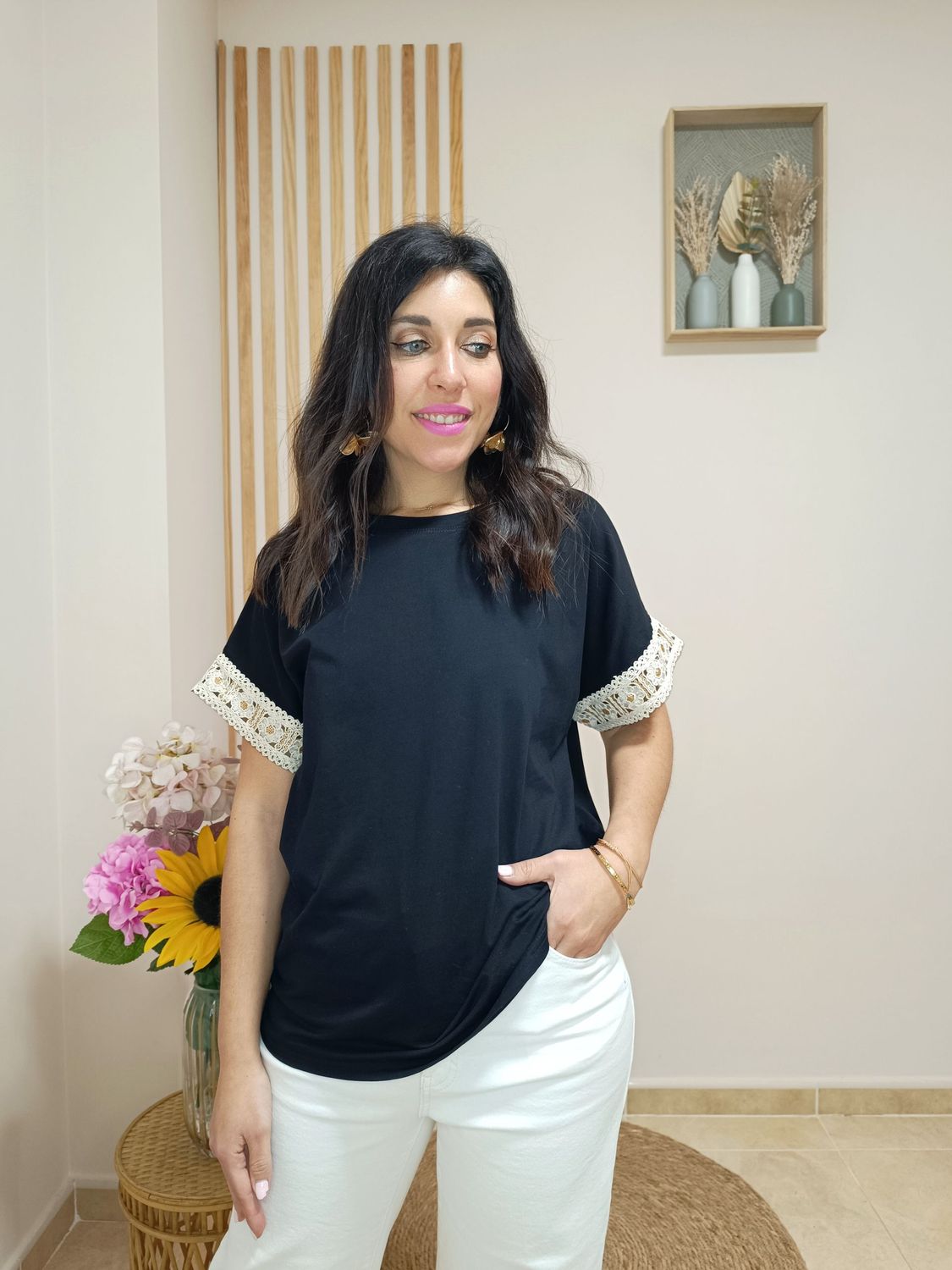 Camiseta en manga corta de color negro y con detalle en el filo de las mangas de cenefa beige con motivo floral y glitter dorado