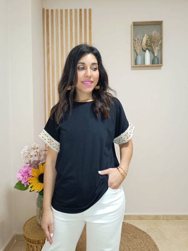 Camiseta en manga corta de color negro y con detalle en el filo de las mangas de cenefa beige con motivo floral y glitter dorado
