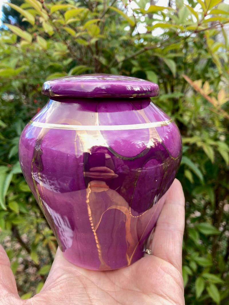 Ancient Creations ceramic pet size cremation urn in dark purple with gold luster design, and real 22 karat gold banding.