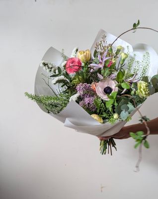 spring bouquet in pastels, featuring anemones, ranunculus tulips and spring greens