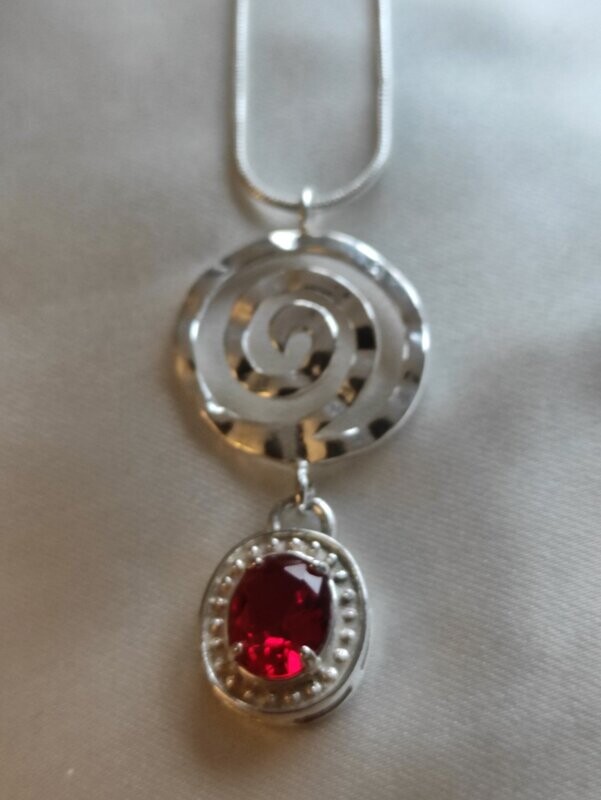 Colgante de topacio rojo y elemento circular en plata.