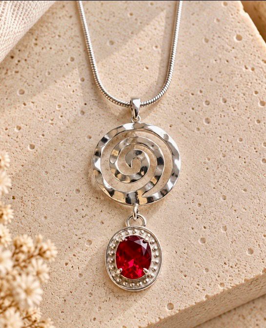 Colgante de topacio rojo y elemento circular en plata.