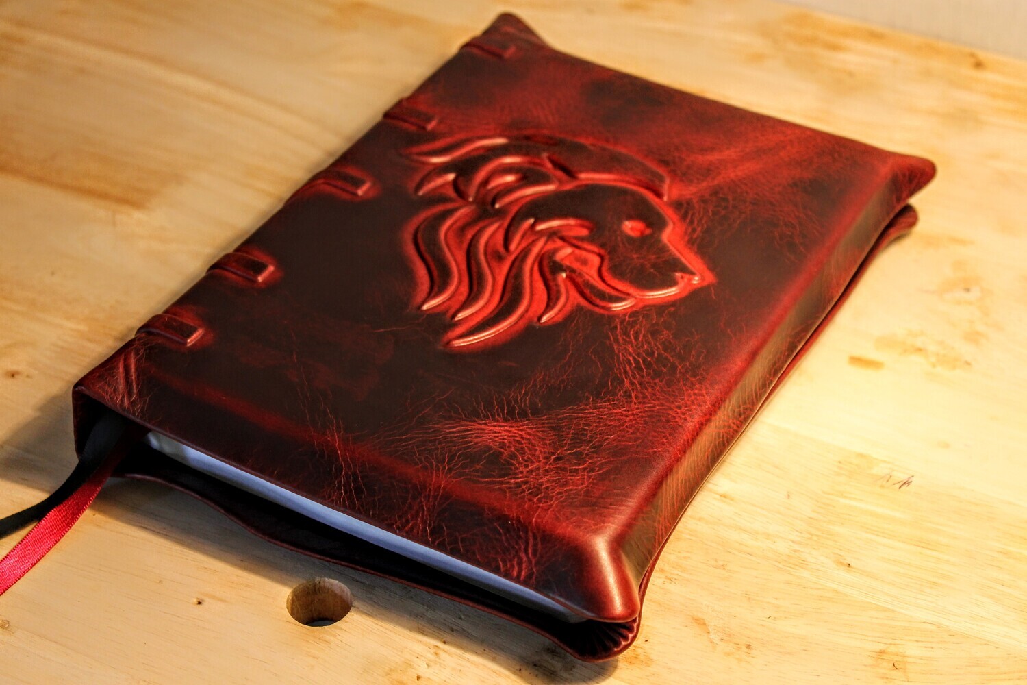 Leather KJV Bible, oxblood cowhide cover with embossed lion and spine details on a wood surface.