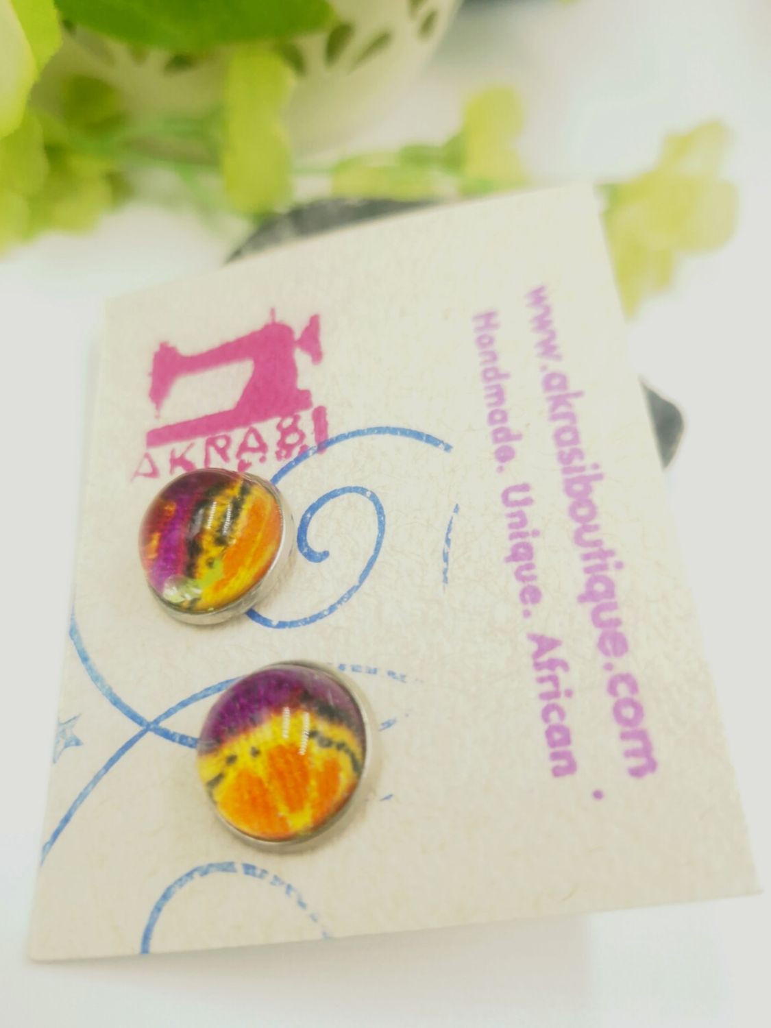 Round deconstructed kente in orange and yellow on silver stud earrings sealed in glass Round deconstructed kente in orange and yellow on silver stud earrings sealed in glass