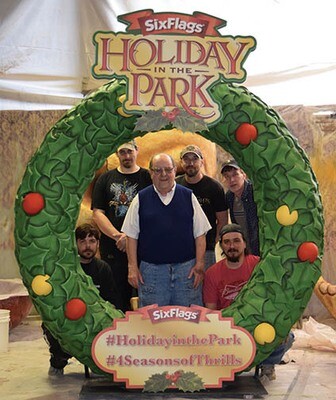 Someone standing inside a Christmas wreath photo opportunity in a theme park.