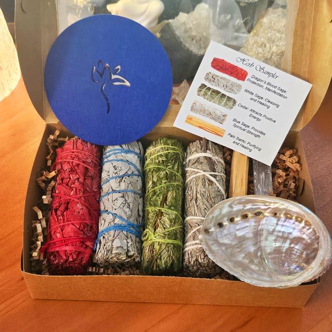 Smudging sampler box with sage bundles, palo santo, selenite wand, abalone shell, heat resistant pad and herb info card.