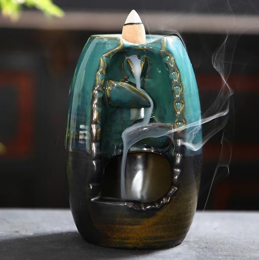 Ceramic backflow waterfall incense burner with smoke cascade and ritual accessories.