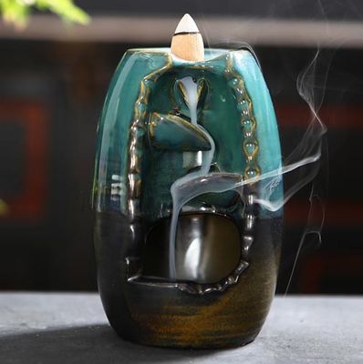Ceramic backflow waterfall incense burner with smoke cascade and ritual accessories.