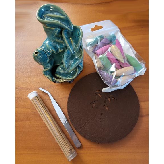 Porcelain lotus incense burner with backflow smoke cascade and ritual accessories.