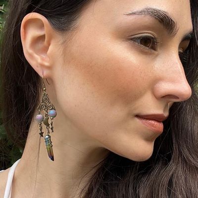 Antique brass Triskele earrings with moon and star charms and titanium quartz crystal, displayed as celestial jewelry.