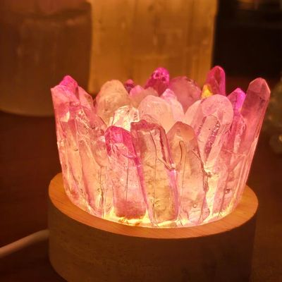 Quartz crystal lamp glowing with warm yellow, pink, and purple light on a round wooden base