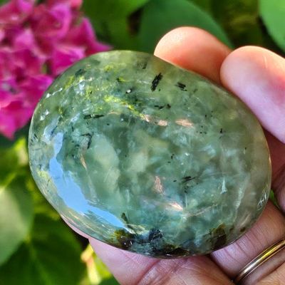 Hand‑polished Prehnite palm stone with soft green glow for healing and intuition.