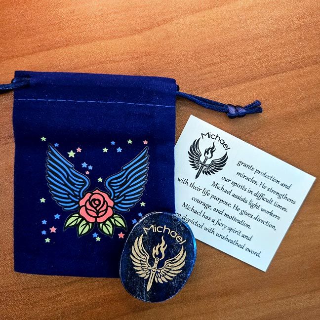 Lapis Michael stone beside a blue winged pouch with a rose design and a printed card behind it