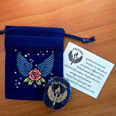 Lapis Michael stone beside a blue winged pouch with a rose design and a printed card behind it