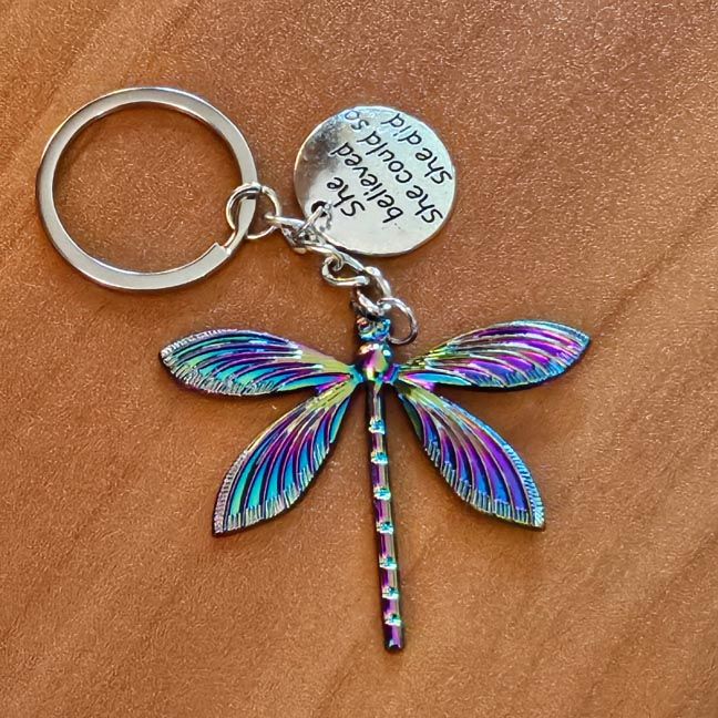 Titanium‑aura dragonfly key chain with inspirational medallion symbolizing courage and transformation.