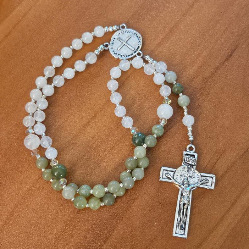 rosary in white and green beads on wood surface