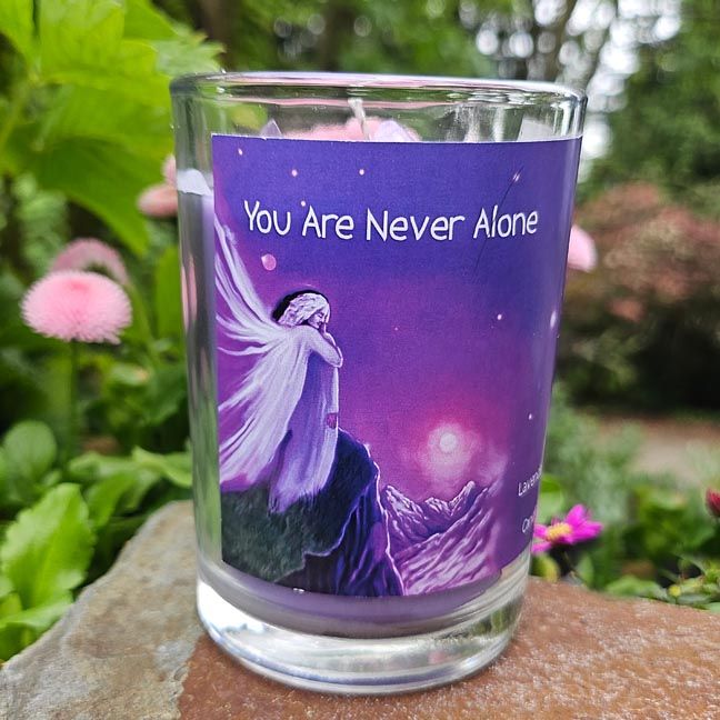 Purple candle labeled You Are Never Alone on a stone outdoors