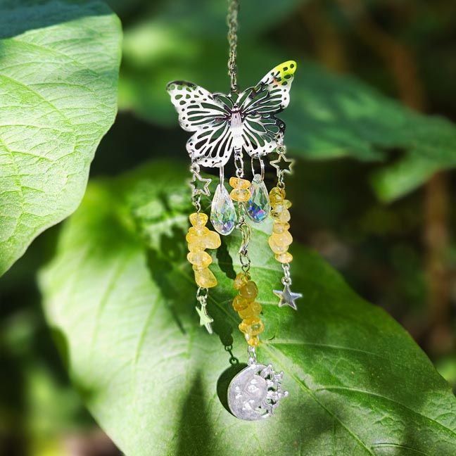 Silver butterfly suncatcher with citrine chips, rainbow prisms, and celestial charms glowing in warm sunlight.