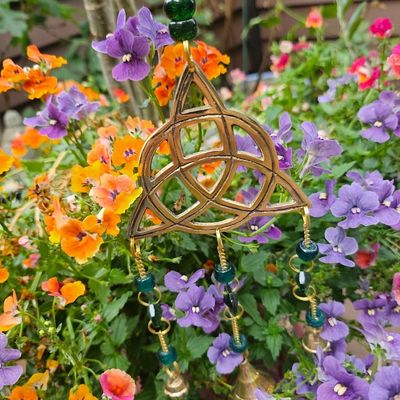 Brass Triquetra wind chime with forest‑green beads, prisms, and bells for unity and protection.