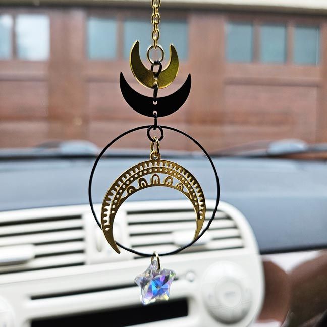 Celestial car charm with gold and black moons, aura star, and rainbow prism for twilight magic.
