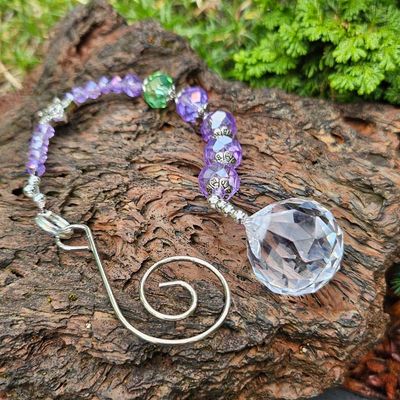 Violet and emerald bead charm with silver star and prism that creates rainbow light.