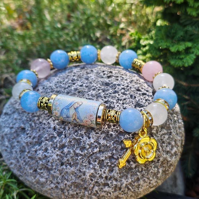 Bracelet with rose quartz, clear quartz, blue chalcedony beads, Mary centerpiece, and small golden cross and rose charms.