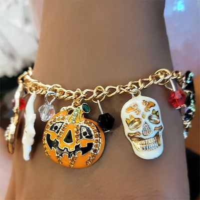 Colorful Halloween charms bracelet with enamel pumpkin, cat, ghost, spider, and skull charms.