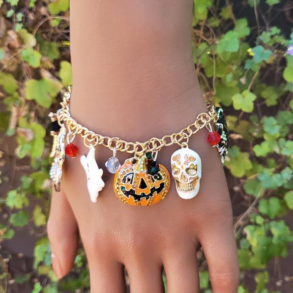 Colorful Halloween charms bracelet with enamel pumpkin, cat, ghost, spider, and skull charms.