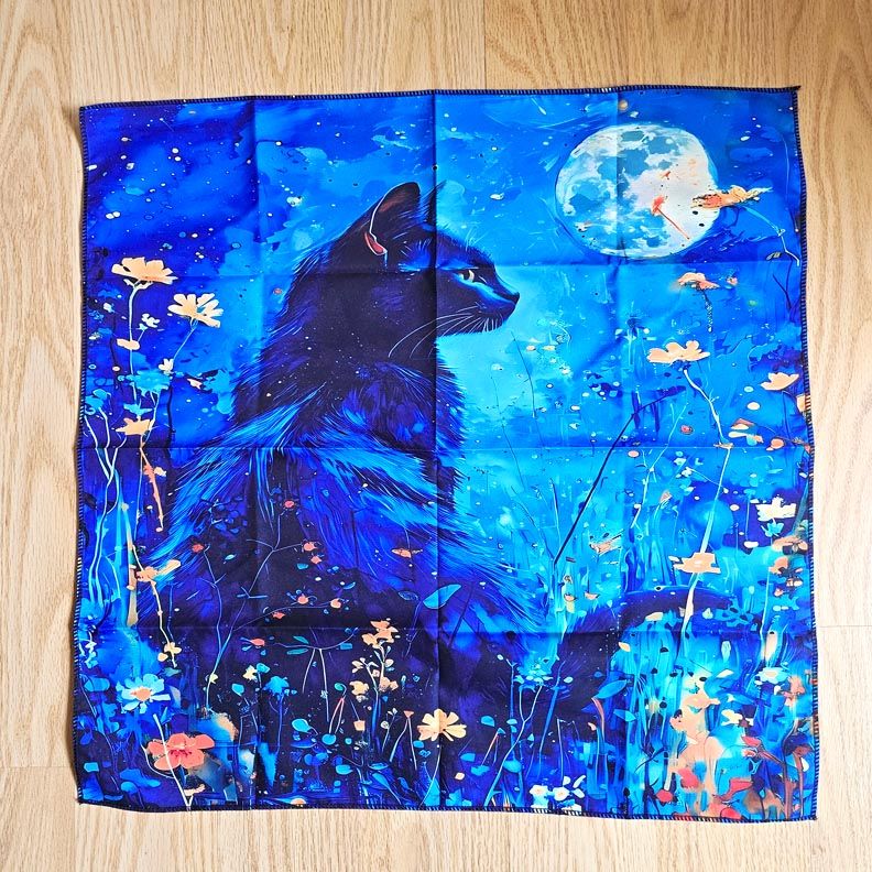 Black cat gazing at full moon amid blue wildflowers on mystical altar cloth.
