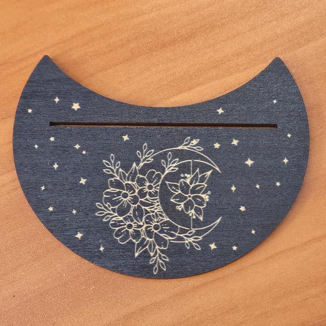 Black wooden crescent moon card stand with gold floral engraving, perfect for displaying tarot or oracle cards.